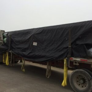 Worker securing a heavy-duty cargo tarp on a truck